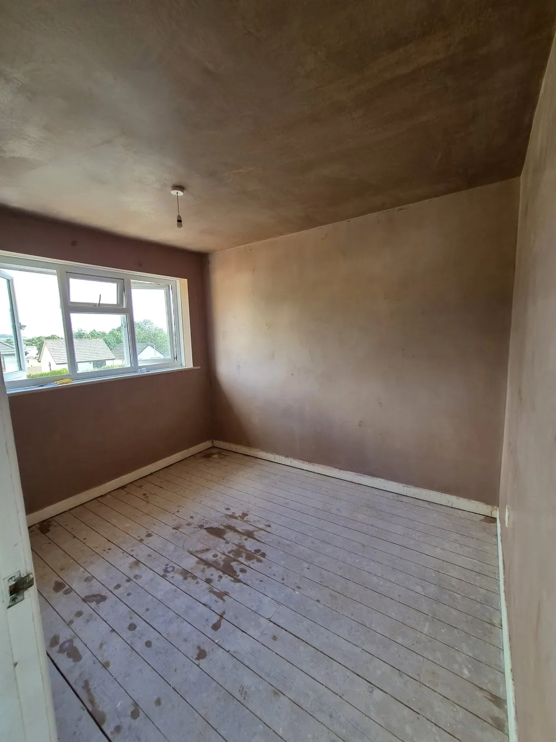 Freshly plastered walls and ceiling in a room with a bay window